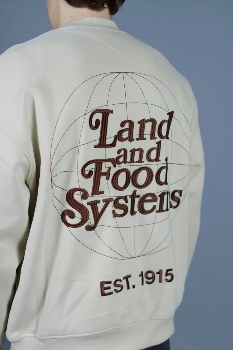 Close-up of embroidered lettering on the back of a cream crewneck