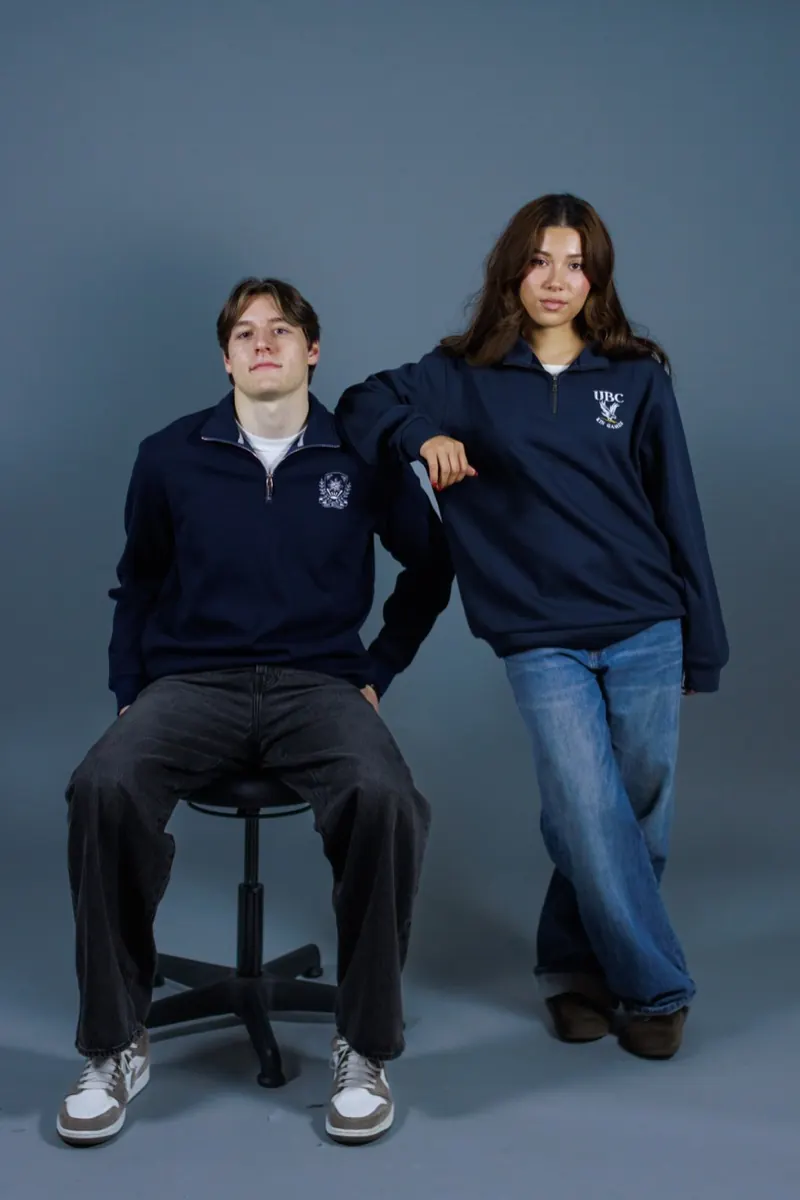 Two models in navy quarter-zips with a small chest crest